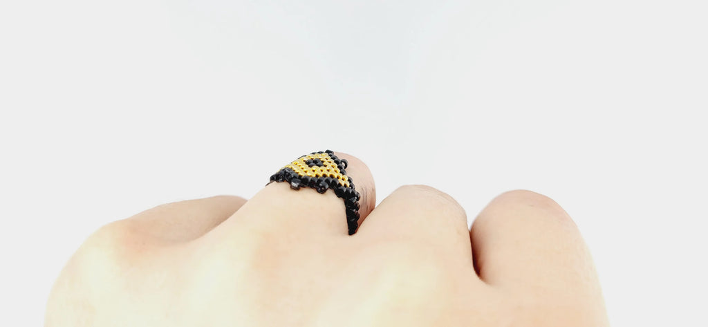Modelo con un anillo cosido con cristal japonés dorado y negro brillante