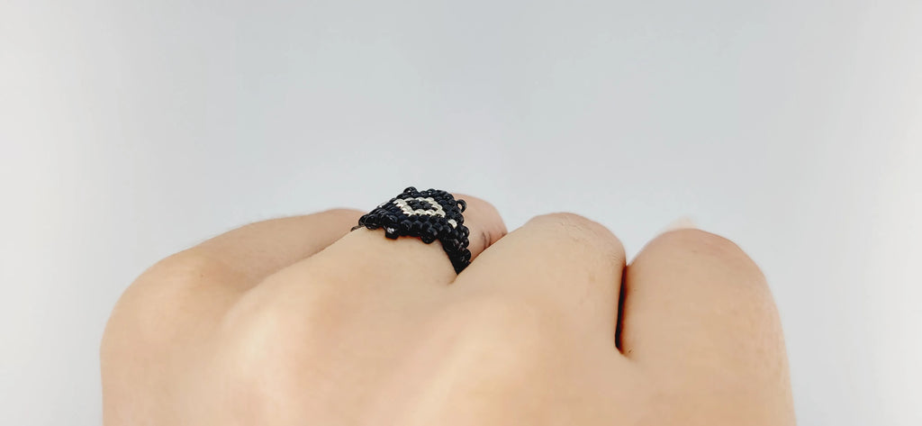 Modelo con un anillo cosido con cristal japonés negro brillante, mate y plateado