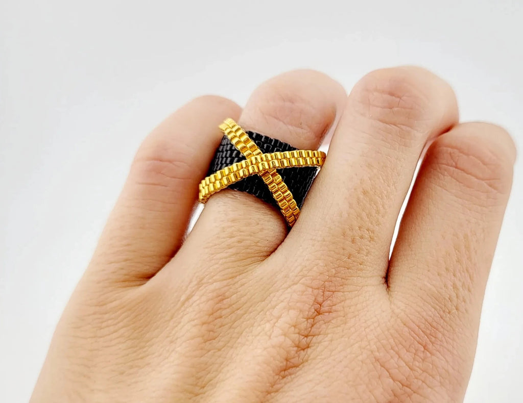 Modelo con un anillo cosido con cristal japonés negro brillante y dorado