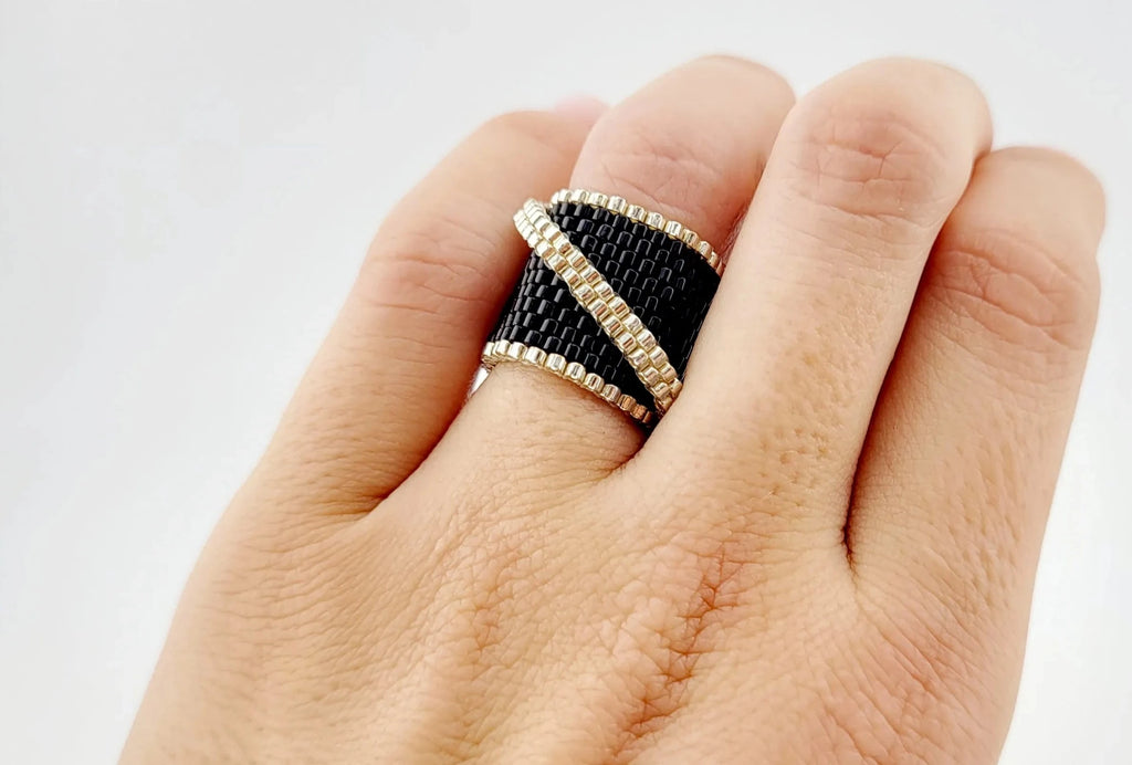Modelo con un anillo cosido con cristal japonés negro brillante con una línea plateada
