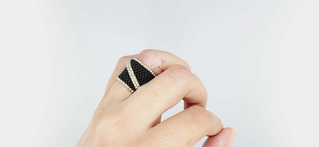 Modelo con un anillo cosido con cristal japonés negro brillante con una línea plateada